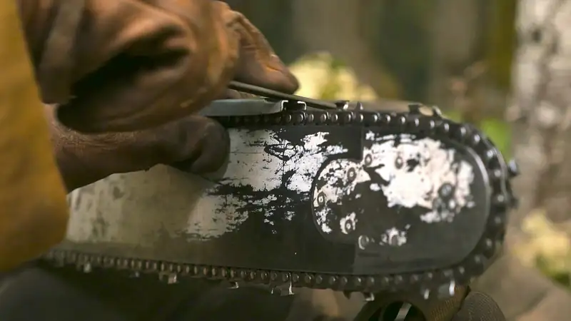 Close-up of a chainsaw chain on its bar: the links, rivets and the drive links in the bar groove